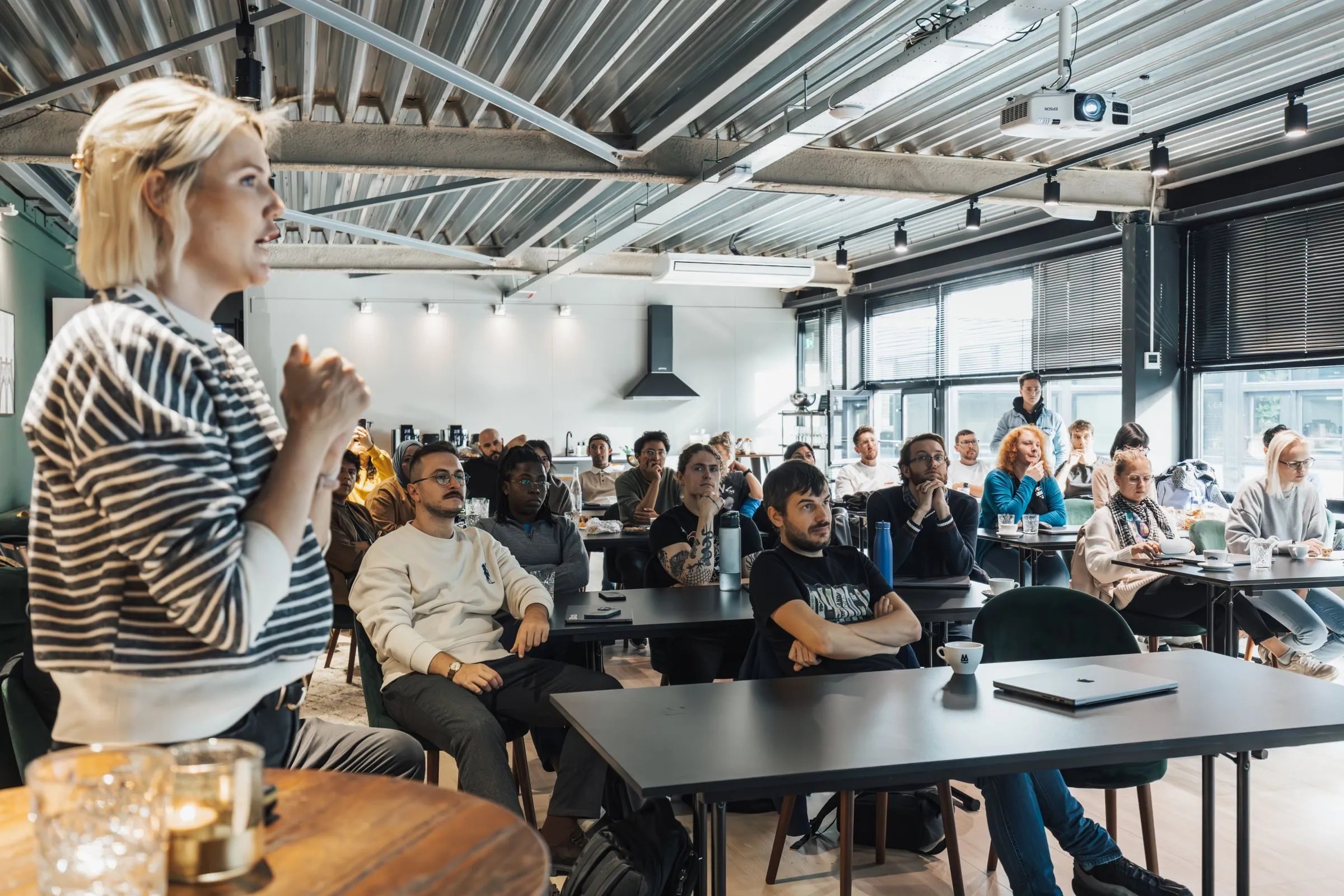 A dynamic speaker engaging a diverse audience in a modern workshop setting.